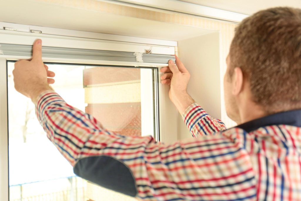 Mężczyzna montuje rolety bezinwazyjne